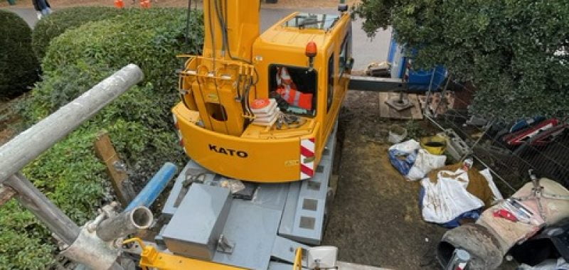 Small mobile crane operating on reduced outriggers to avoid obstacles