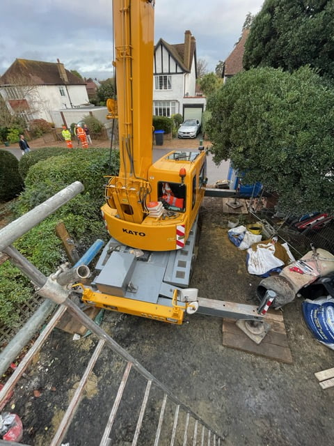 Small mobile crane operating on reduced outriggers to avoid obstacles
