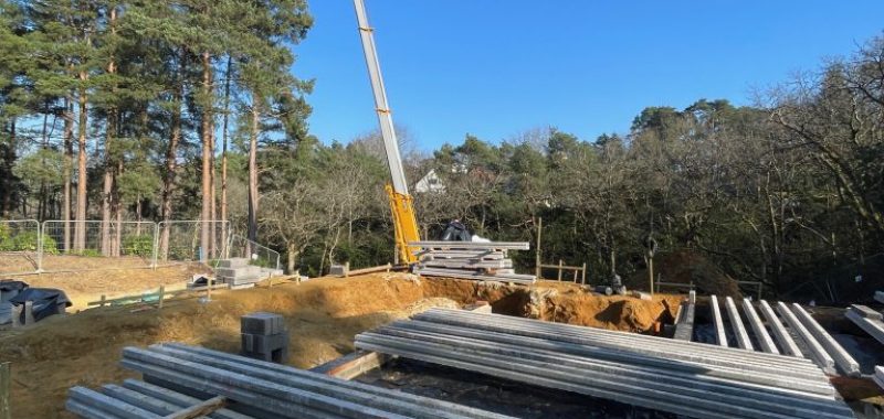 Mobile crane on site lifting concrete Beams