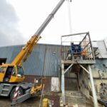 Crane lifting machinery from a gantry