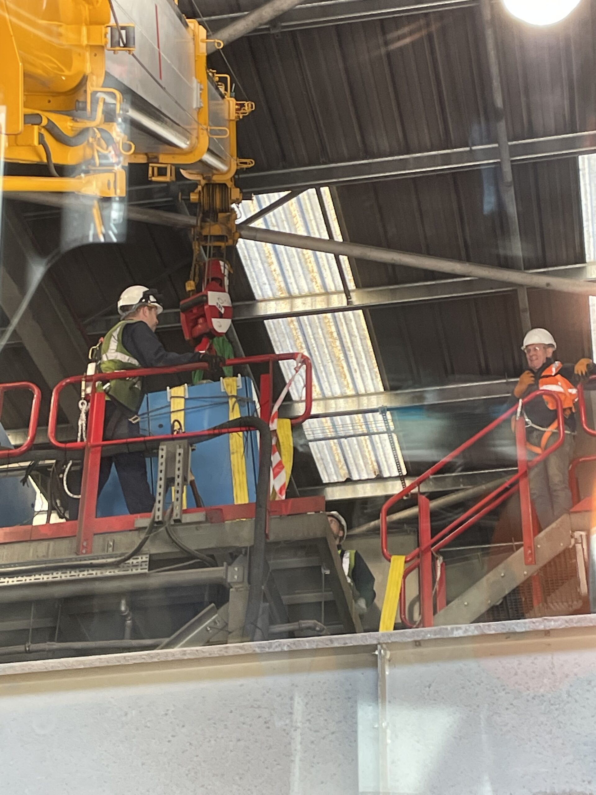 Mobile crane inside a building lifting a compressor